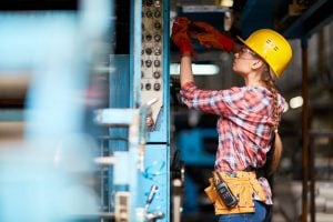 technician with screwdriver repairing machine at plant