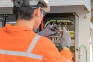 Electrical and instrument technician wiring cable at terminal and junction box, an oil rig worker maintenance electric system on offshore platform.